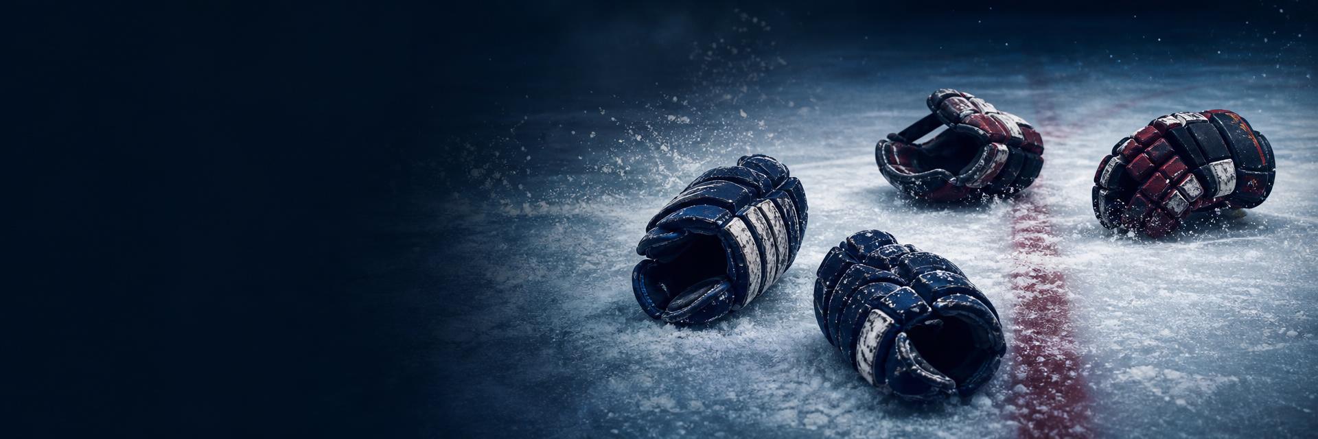 Deep navy hockey gloves resting on bright white ice beside a puck
